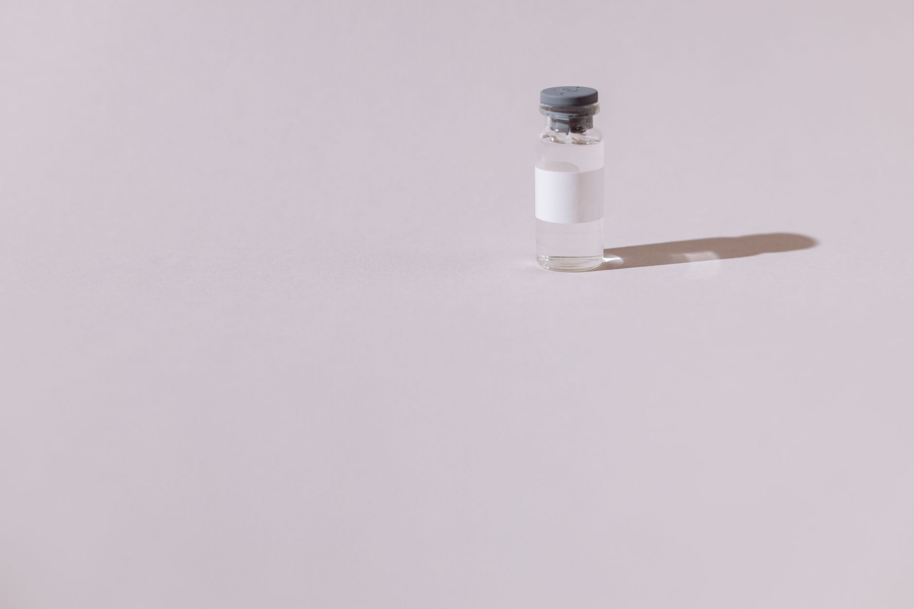 Glass pharmaceutical vial on a plain background.